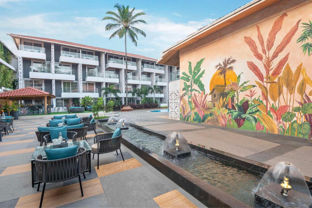 a hotel with tables and chairs and a mural at Hyatt Place Goa Candolim in Candolim a hotel with tables and chairs and a mural at Hyatt Place Goa Candolim in Candolim