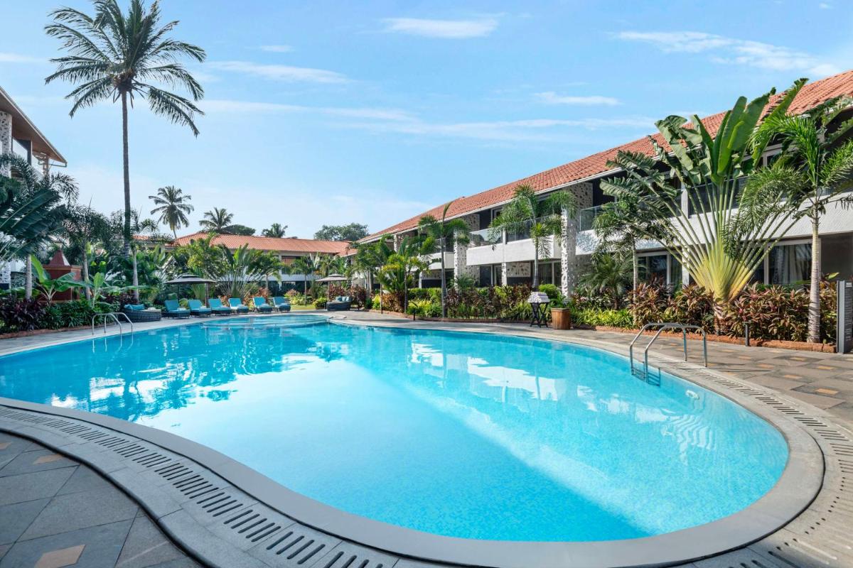 a large swimming pool in a resort with palm trees at Hyatt Place Goa Candolim in Candolim a large swimming pool in a resort with palm trees at Hyatt Place Goa Candolim in Candolim