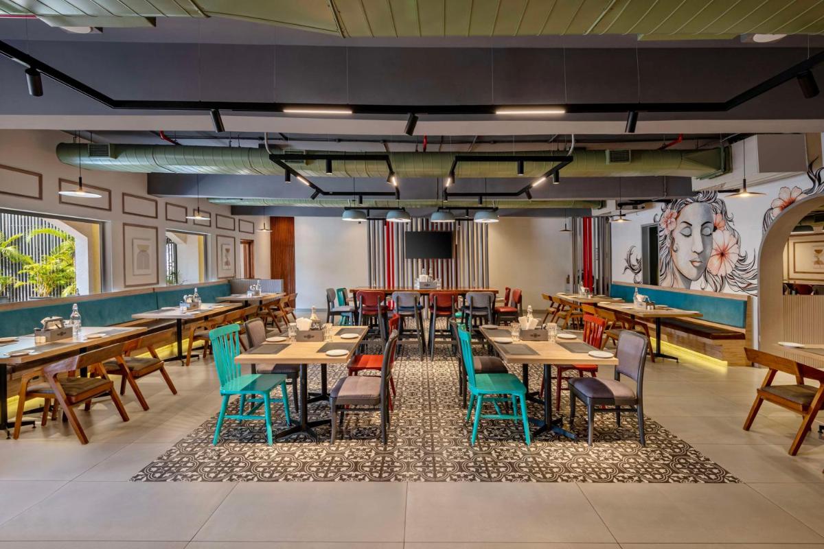 a dining room with wooden tables and chairs at Hyatt Place Goa Candolim in Candolim a dining room with wooden tables and chairs at Hyatt Place Goa Candolim in Candolim