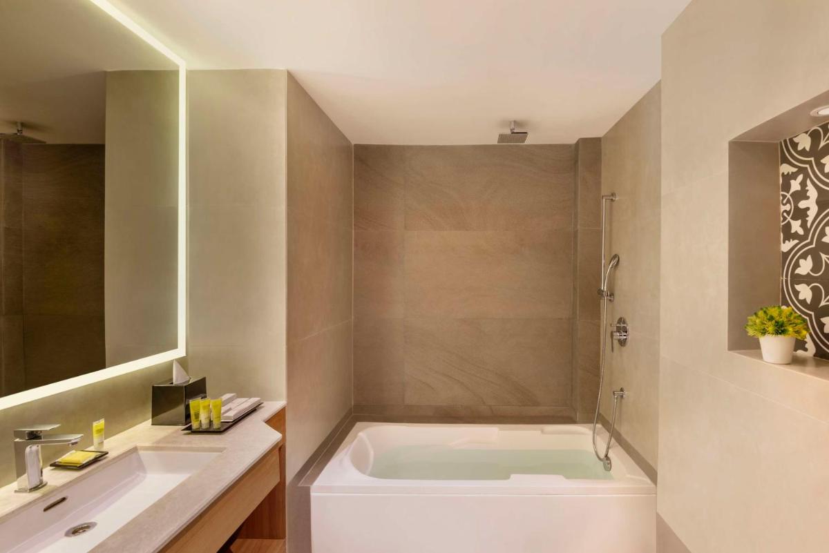 a bathroom with a tub and a sink at Hyatt Place Goa Candolim in Candolim a bathroom with a tub and a sink at Hyatt Place Goa Candolim in Candolim
