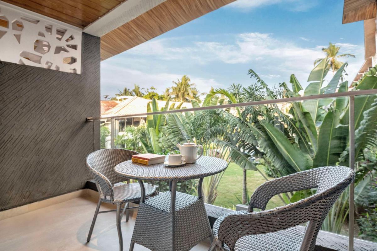 a patio with a table and chairs on a balcony at Hyatt Place Goa Candolim in Candolim a patio with a table and chairs on a balcony at Hyatt Place Goa Candolim in Candolim