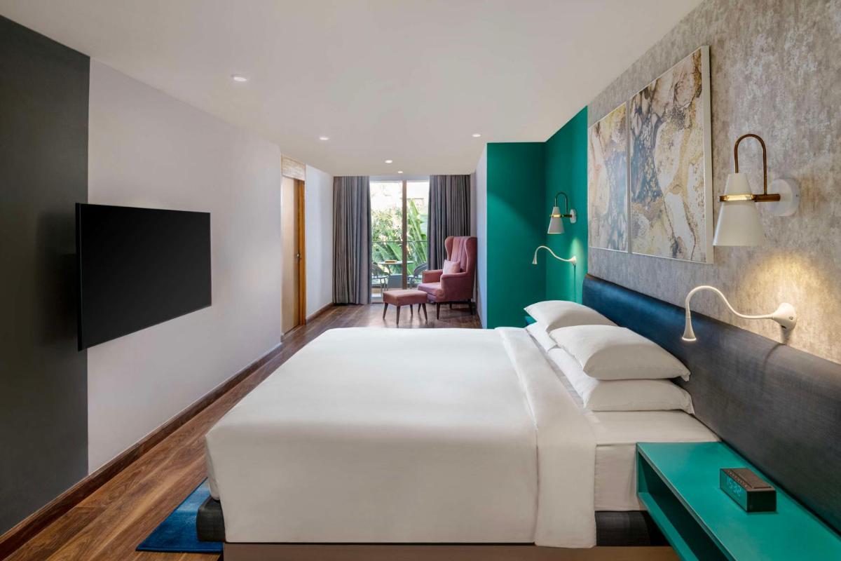 a hotel room with a large bed and a tv at Hyatt Place Goa Candolim in Candolim a hotel room with a large bed and a tv at Hyatt Place Goa Candolim in Candolim
