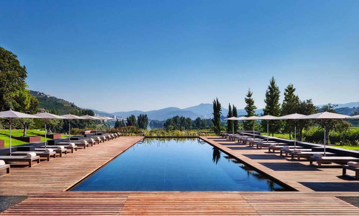 uma piscina com cadeiras e guarda-sóis em um deck de madeira em Six Senses Douro Valley em Lamego