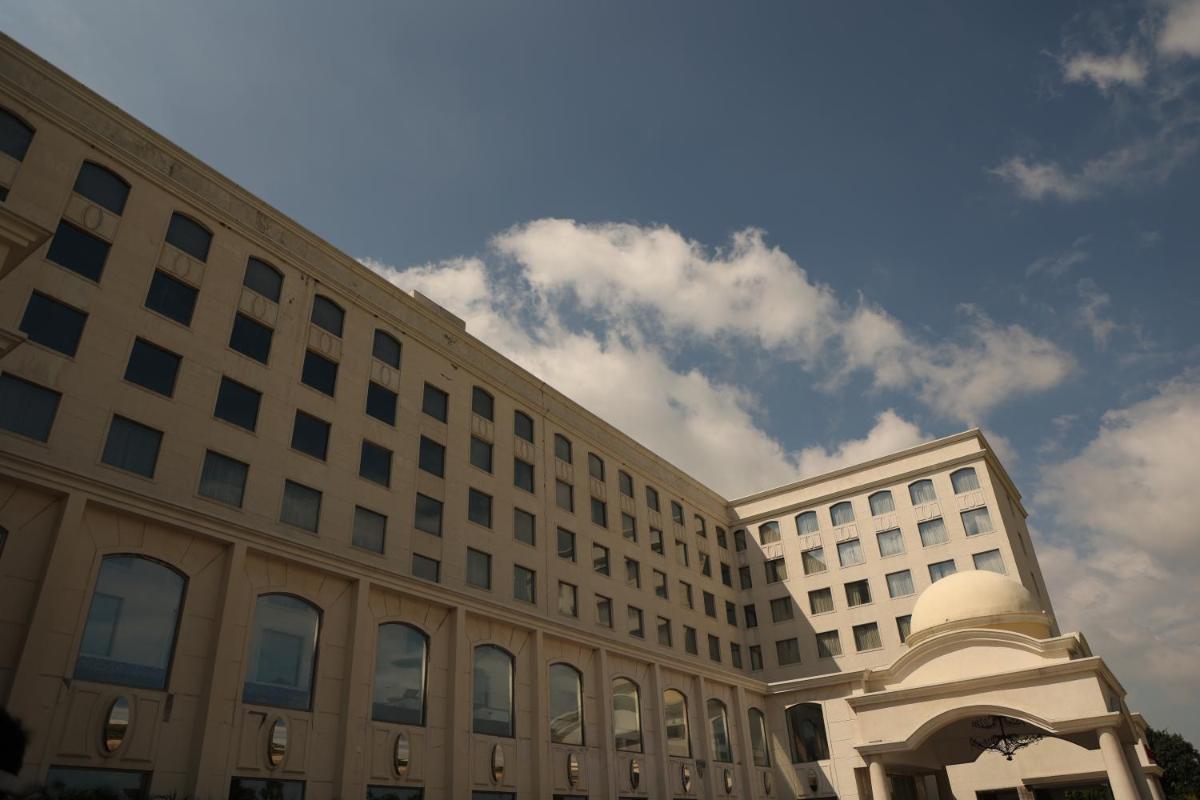 a large white building with a blue sky in the background at Ramada Plaza by Wyndham Lucknow in Lucknow