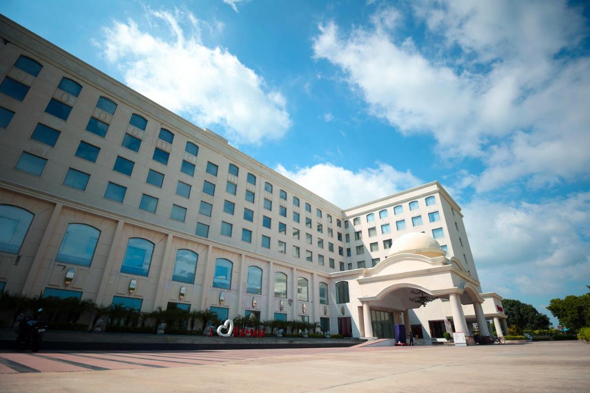 a large white building with a large at Ramada Plaza by Wyndham Lucknow in Lucknow