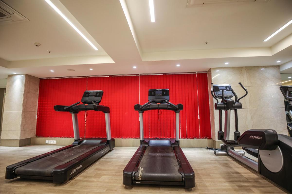 a gym with two treadmills and a red wall at Ramada Plaza by Wyndham Lucknow in Lucknow