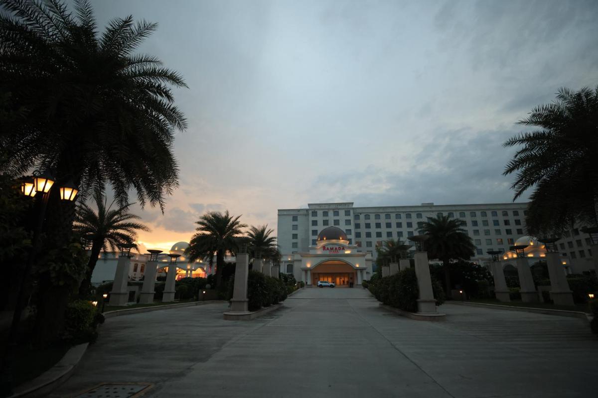 a large building with palm trees in front of it at Ramada Plaza by Wyndham Lucknow in Lucknow