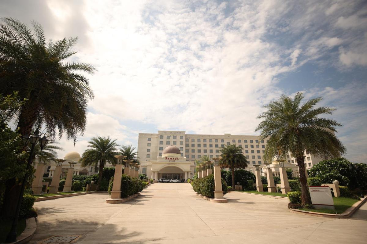 a large building with palm trees in front of it at Ramada Plaza by Wyndham Lucknow in Lucknow