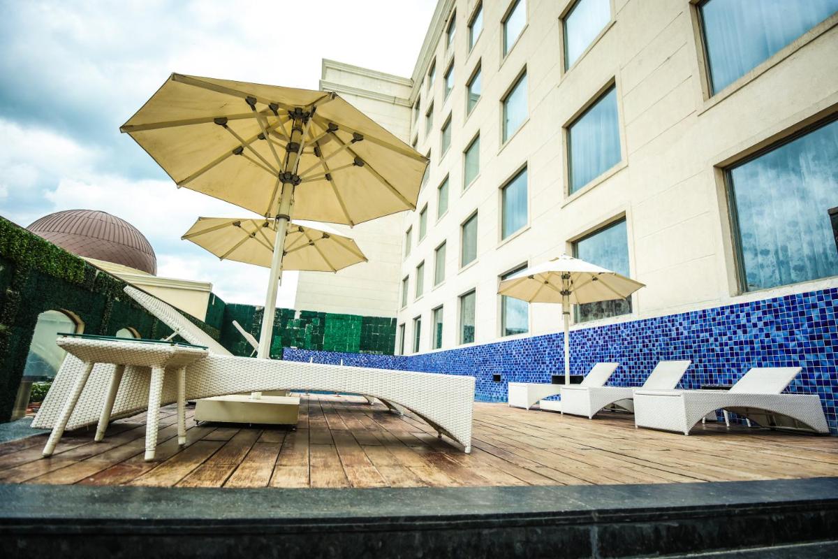 a group of chairs and umbrellas on a deck at Ramada Plaza by Wyndham Lucknow in Lucknow