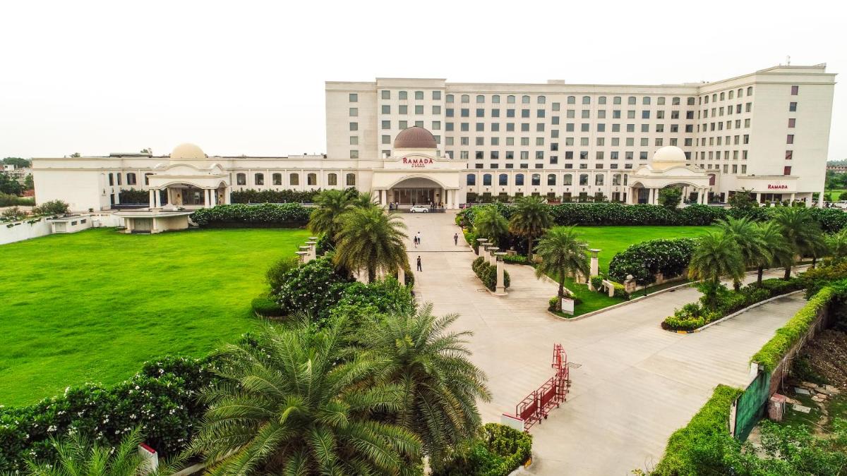 a large building with palm trees in front of it at Ramada Plaza by Wyndham Lucknow in Lucknow