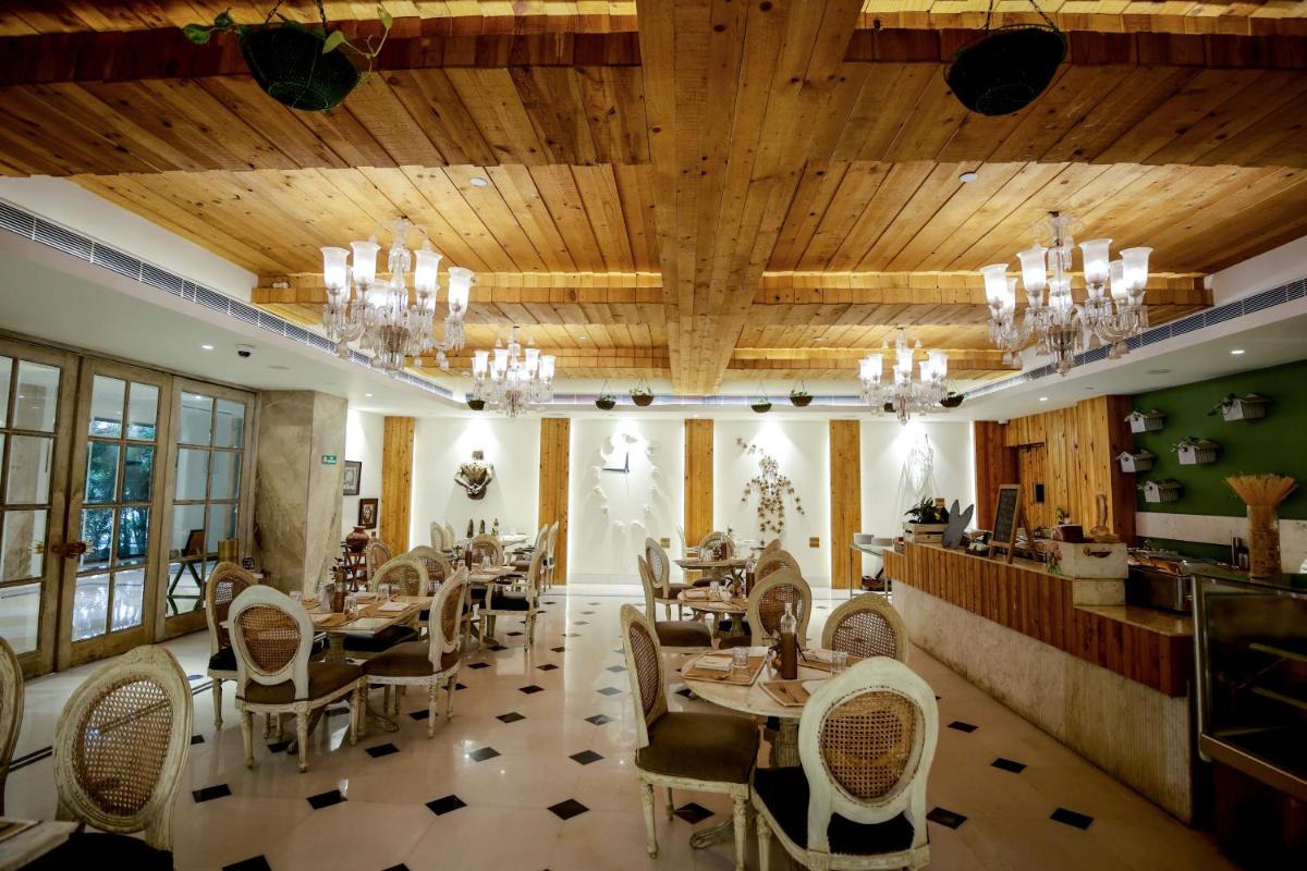 a restaurant with wooden ceilings and tables and chairs at Ramada Plaza by Wyndham Lucknow in Lucknow