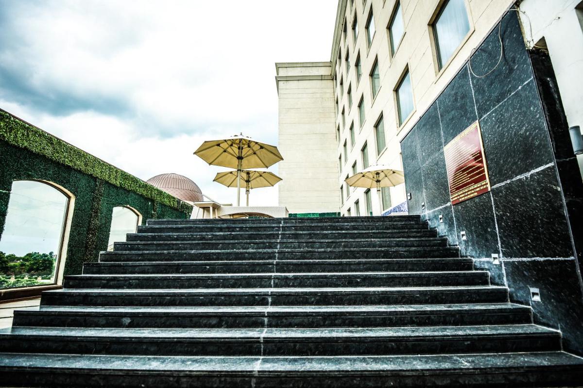 a set of stairs in front of a building with an umbrella at Ramada Plaza by Wyndham Lucknow in Lucknow