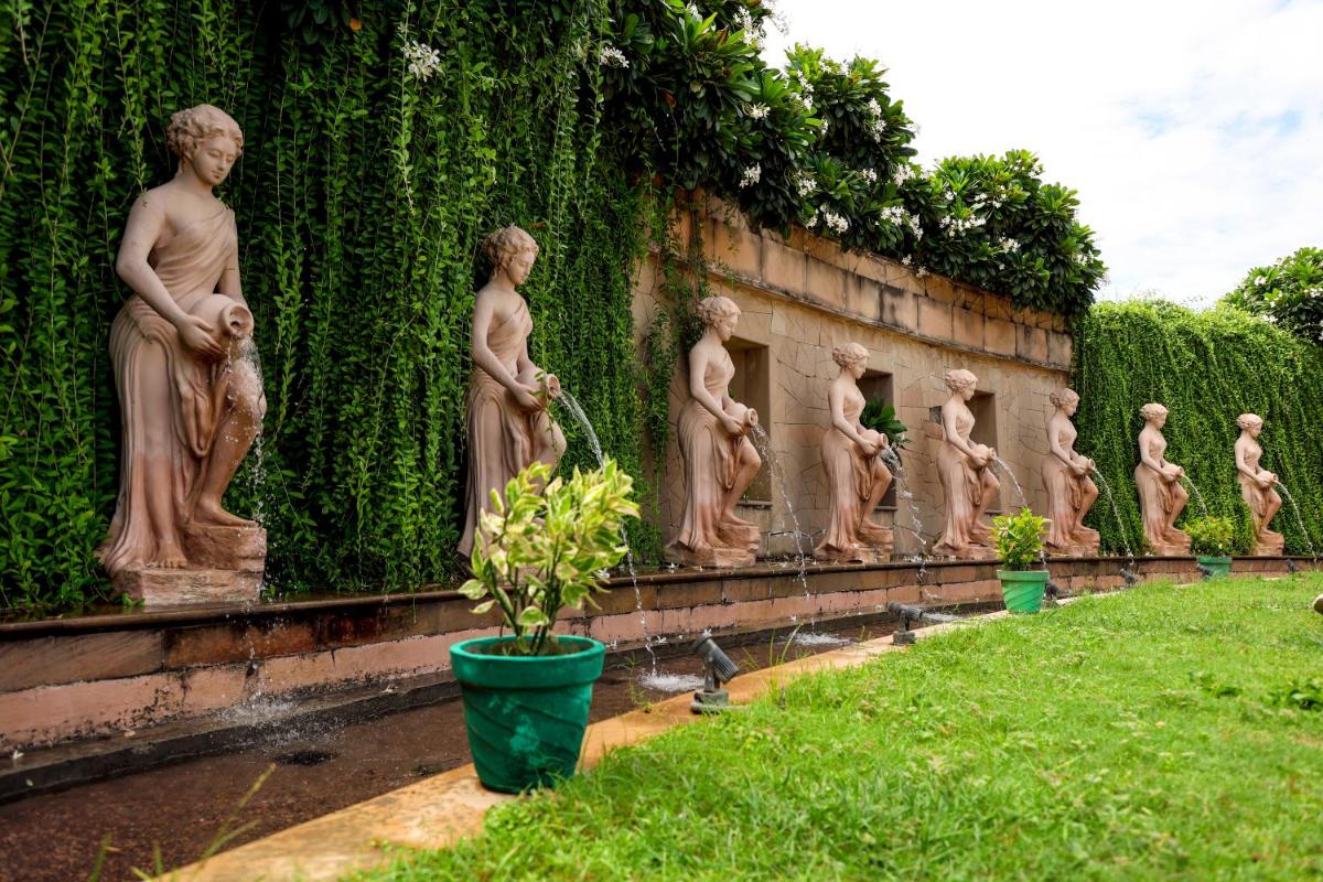 a row of statues on a wall in a garden at Ramada Plaza by Wyndham Lucknow in Lucknow