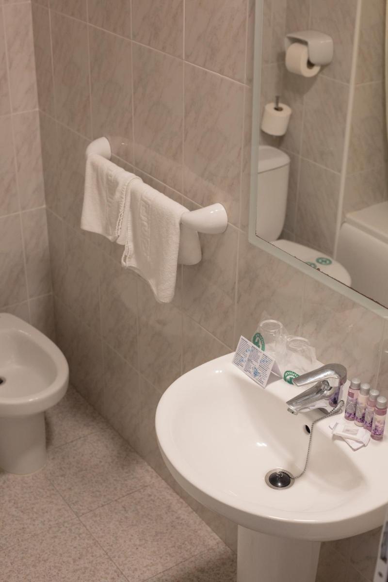 Un baño con lavabo, inodoro y espejo. en Cleopatra Spa Hotel, en Lloret de Mar