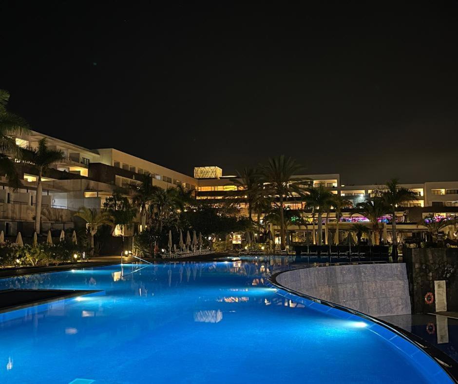 Una gran piscina azul por la noche con edificios. en Hotel Costa Calero Thalasso & Spa, en Puerto Calero
