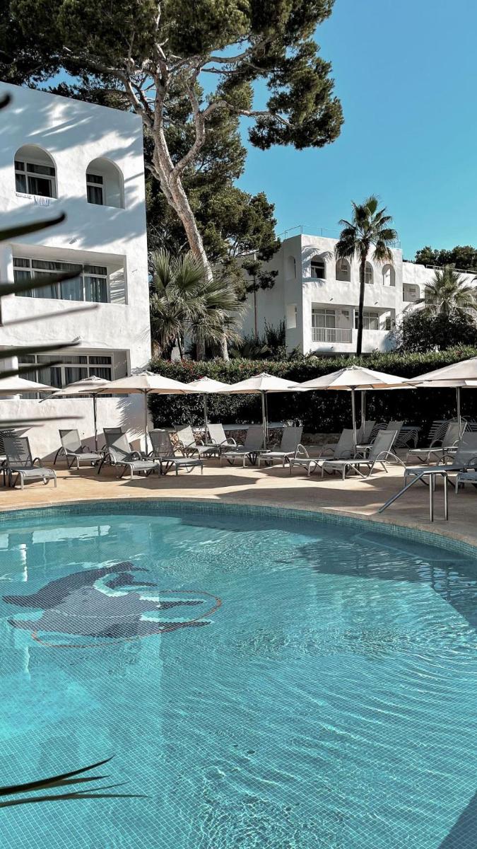 Una piscina con sillas y sombrillas al lado de un edificio. en Prinsotel Alba & Spa, en Cala d´Or