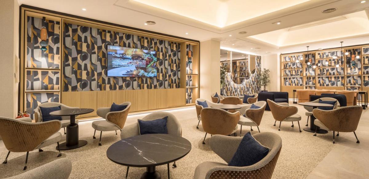 Una sala de espera con sillas y mesas y un televisor. en Ilunion Les Corts Spa, en Barcelona