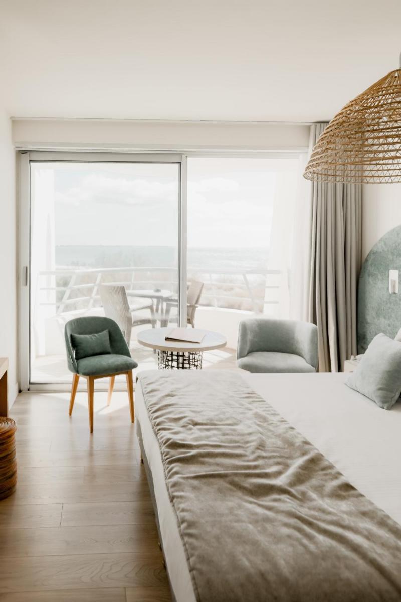 une chambre d'hôtel avec deux lits et une grande fenêtre dans l'établissement Hôtel Les Corallines - Thalasso & Resort, à La Grande Motte