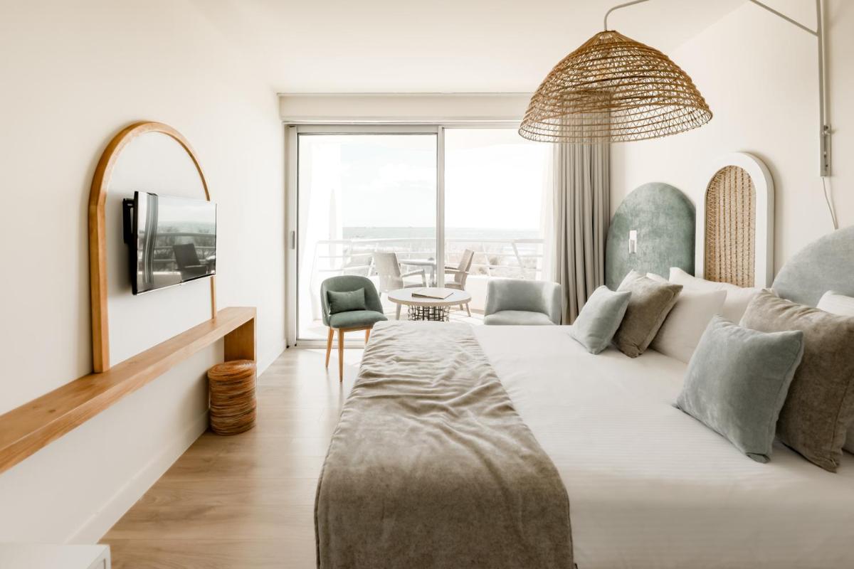 une chambre avec un grand lit et un salon dans l'établissement Hôtel Les Corallines - Thalasso & Resort, à La Grande Motte