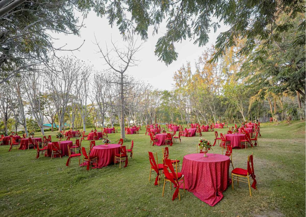 a group of tables and chairs with red table cloth at Essentia Luxury Resort & Spa Udaipur in Udaipur