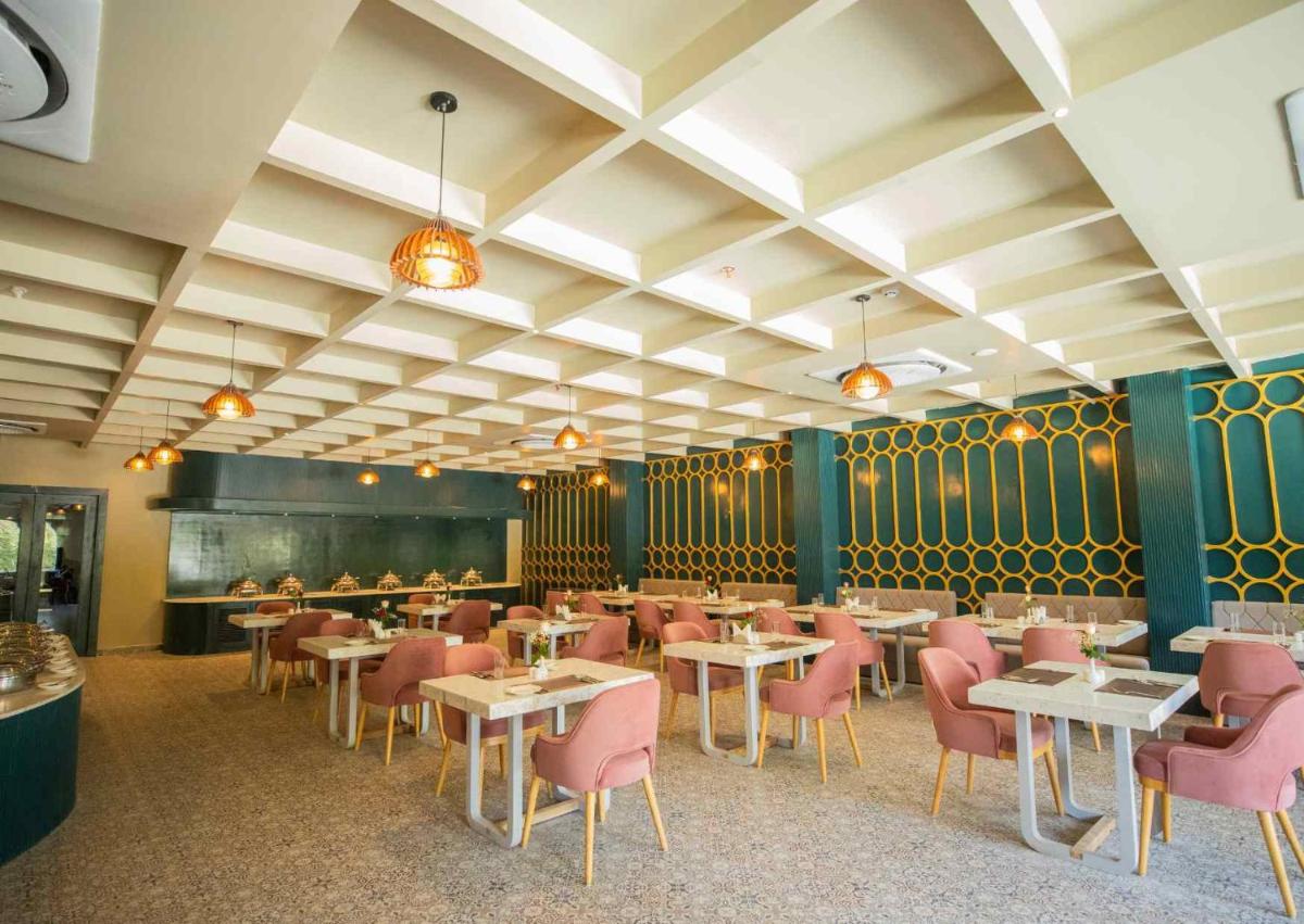 a dining room with tables and pink chairs at Essentia Luxury Resort & Spa Udaipur in Udaipur