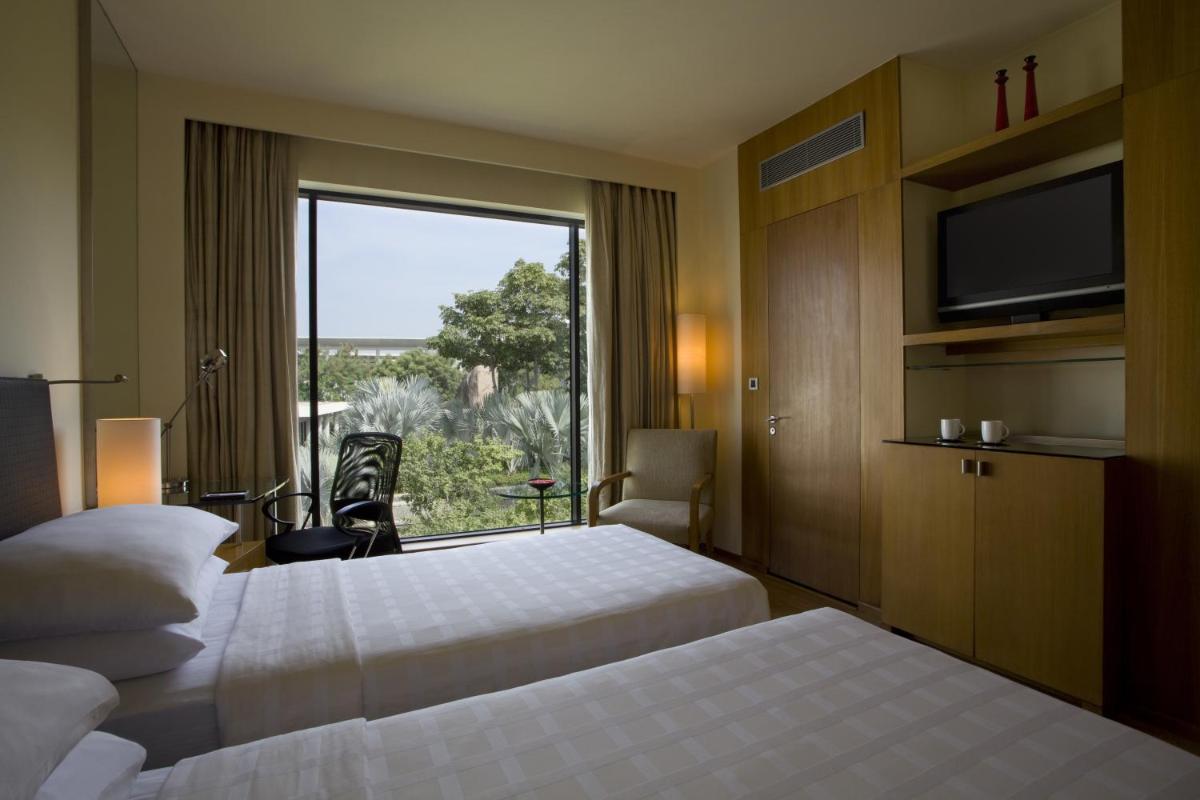 a hotel room with two beds and a large window at Hyatt Hyderabad Gachibowli in Hyderabad