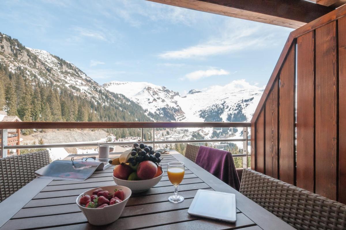 - une table avec un bol de fruits sur un balcon avec des montagnes dans l'établissement Résidence Pierre & Vacances Premium Les Terrasses d'Hélios, à Flaine