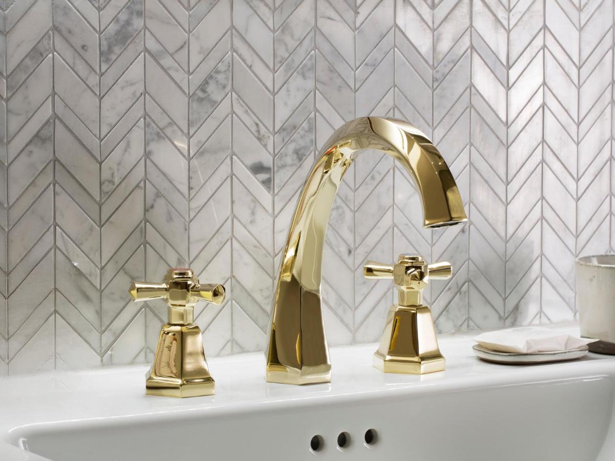 une salle de bains avec deux robinets en or sur un lavabo dans l'établissement Maison Bréguet, à Paris