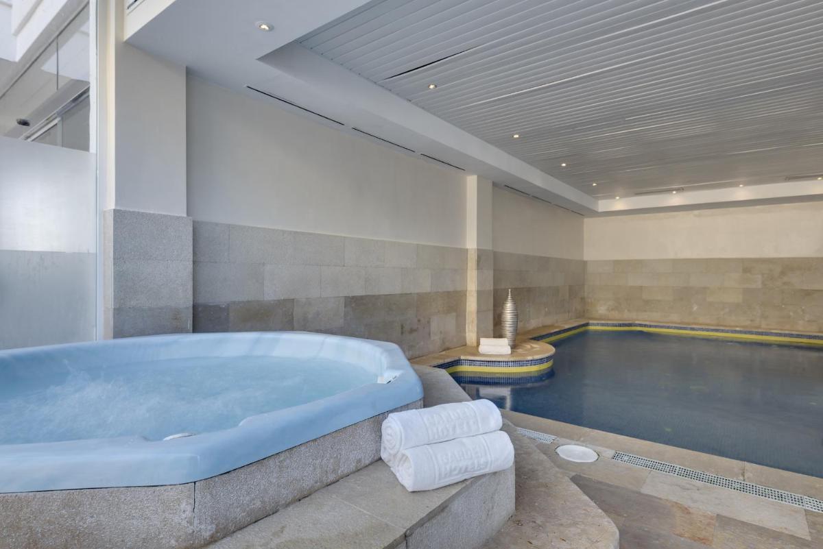 Un baño grande con bañera y piscina. en Alcudia Garden Aparthotel, en Puerto de Alcudia