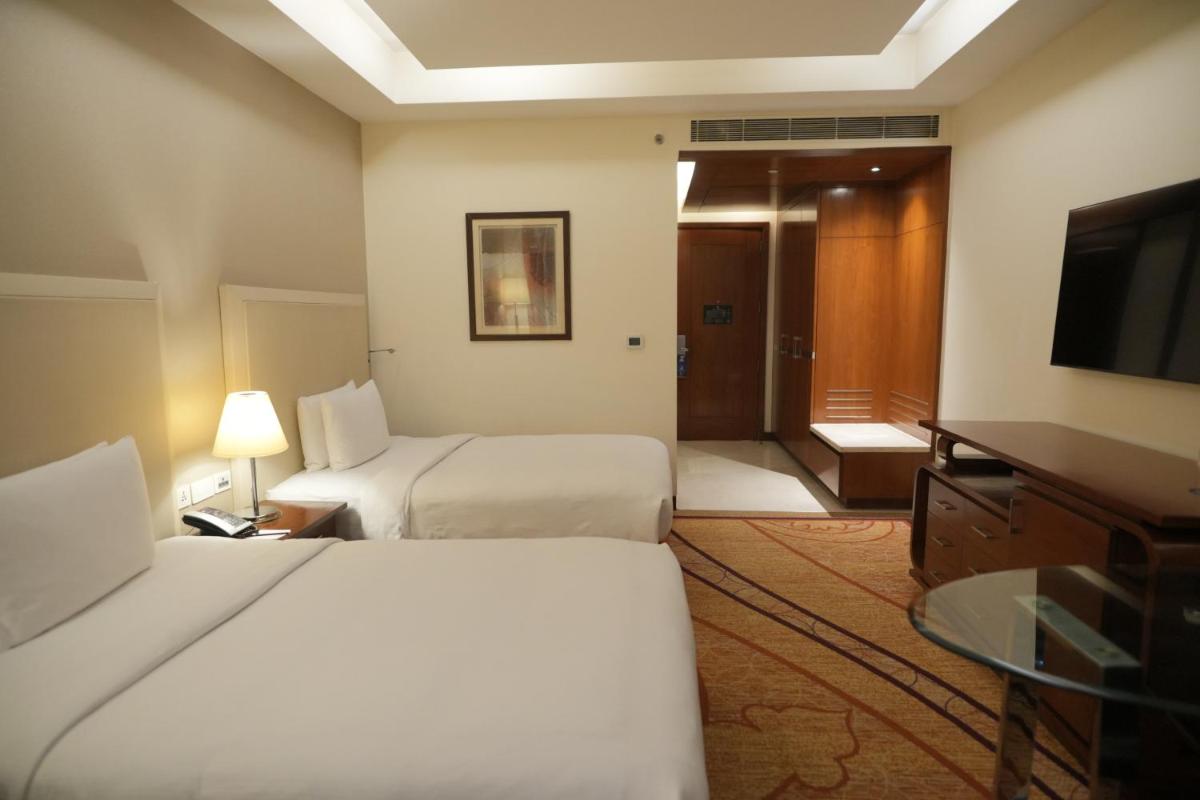 a hotel room with two beds and a flat screen tv at DoubleTree by Hilton Gurgaon New Delhi NCR in Gurgaon