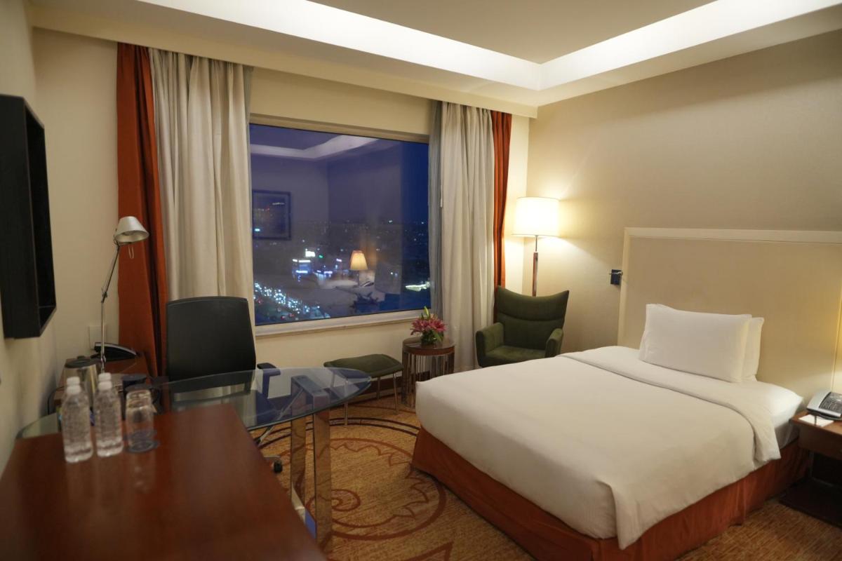 a hotel room with a bed and a desk and a window at DoubleTree by Hilton Gurgaon New Delhi NCR in Gurgaon