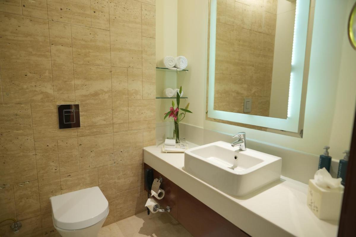 a bathroom with a sink and a toilet and a mirror at DoubleTree by Hilton Gurgaon New Delhi NCR in Gurgaon