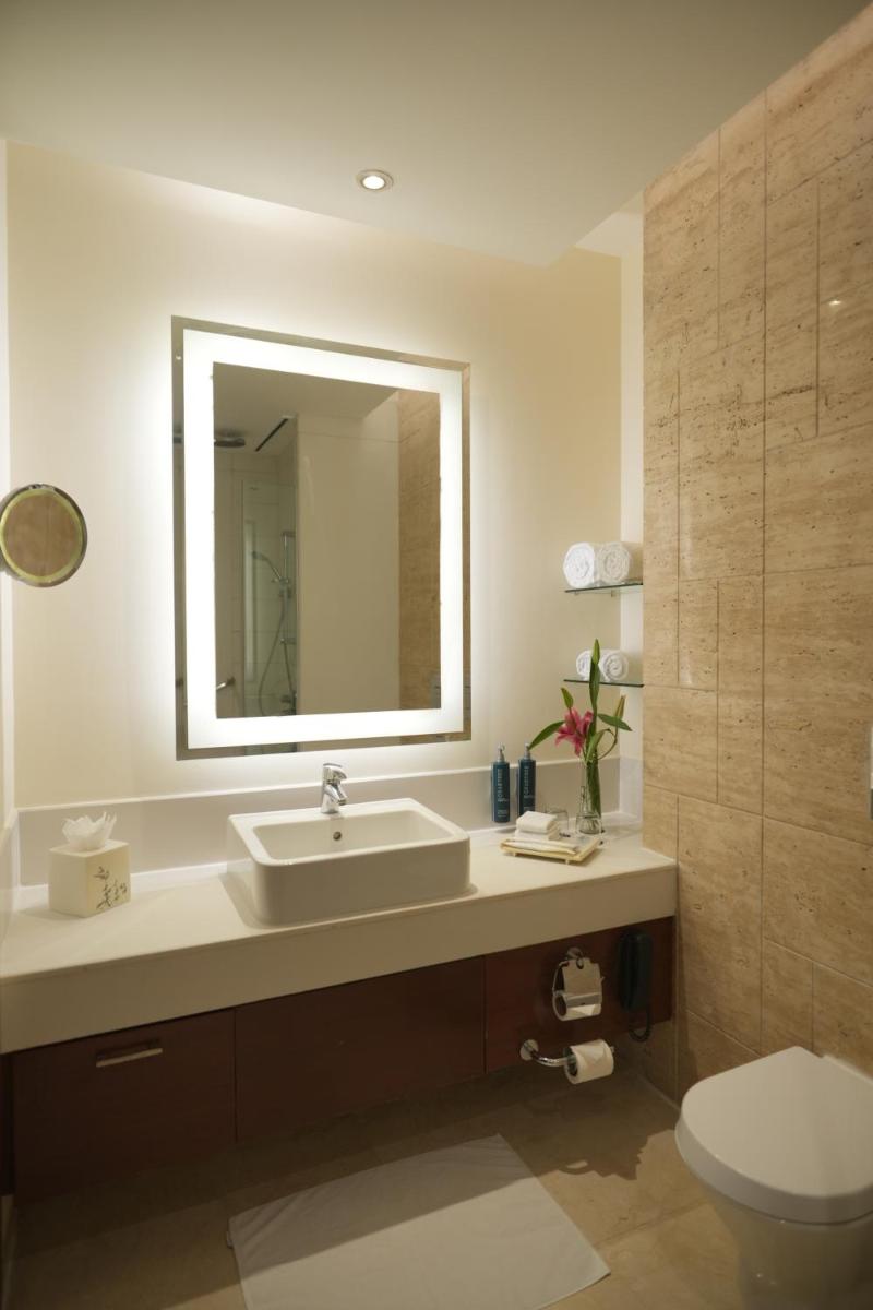 a bathroom with a sink and a toilet and a mirror at DoubleTree by Hilton Gurgaon New Delhi NCR in Gurgaon