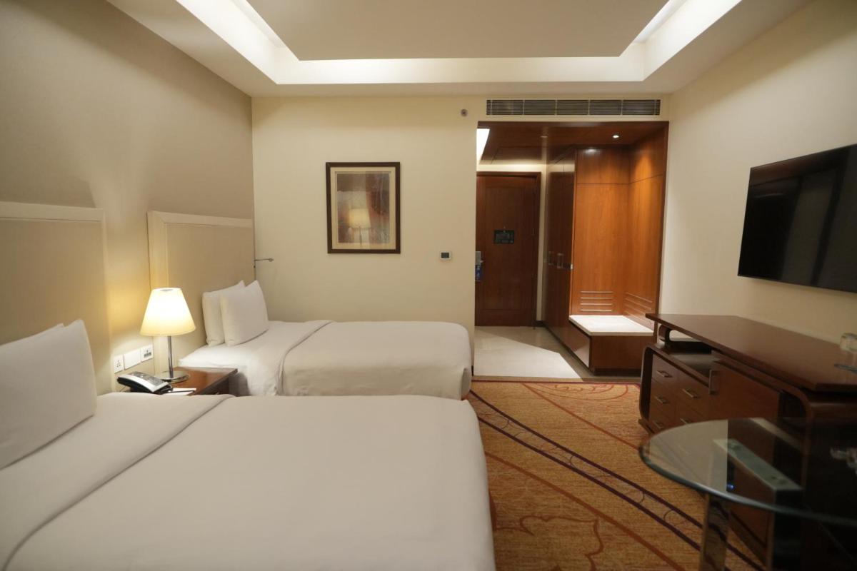 a hotel room with two beds and a flat screen tv at DoubleTree by Hilton Gurgaon New Delhi NCR in Gurgaon
