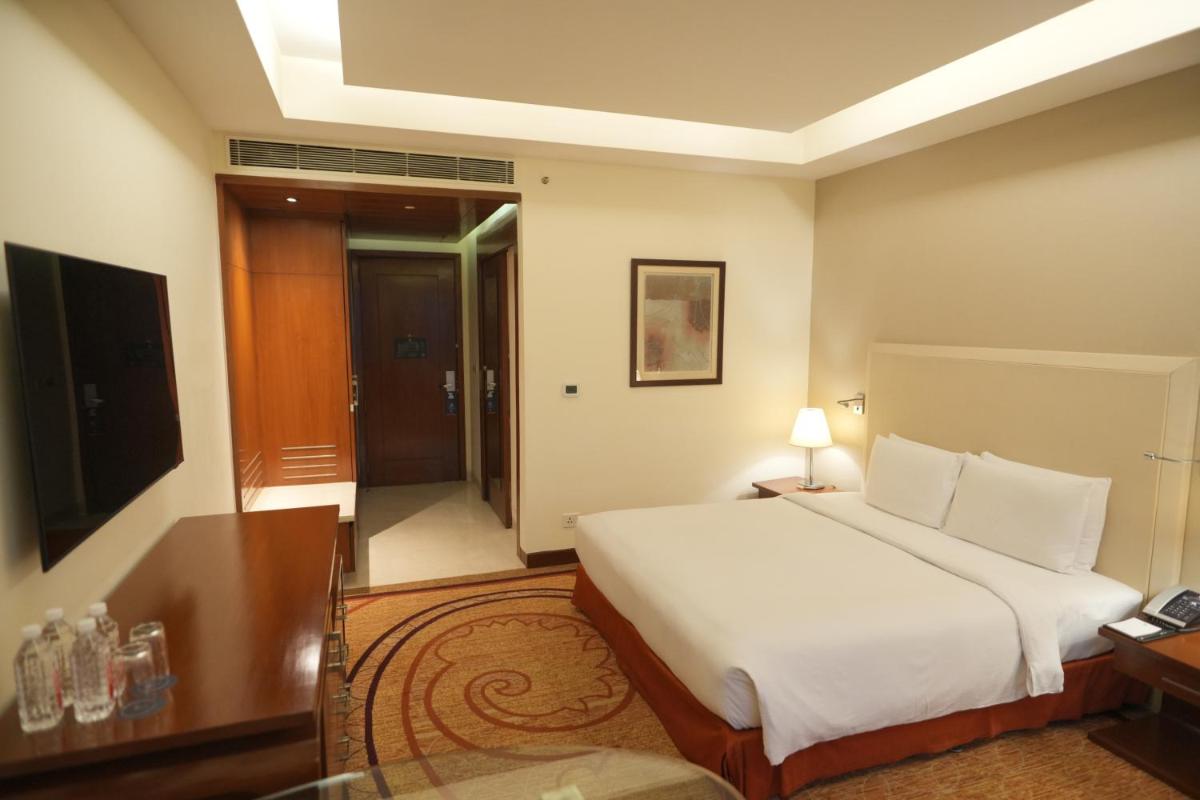 a bedroom with a bed and a desk and a television at DoubleTree by Hilton Gurgaon New Delhi NCR in Gurgaon