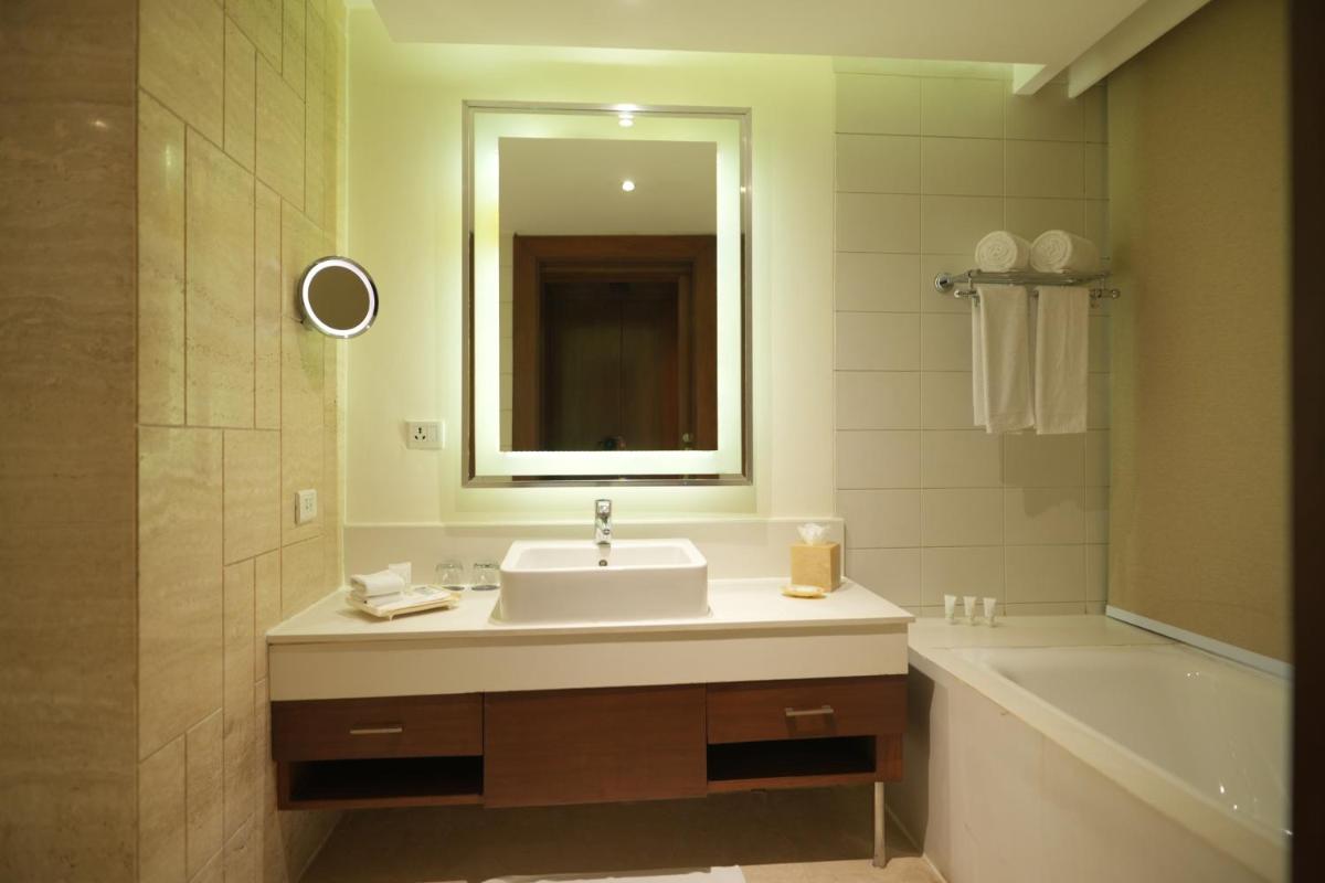 a bathroom with a sink and a tub and a mirror at DoubleTree by Hilton Gurgaon New Delhi NCR in Gurgaon
