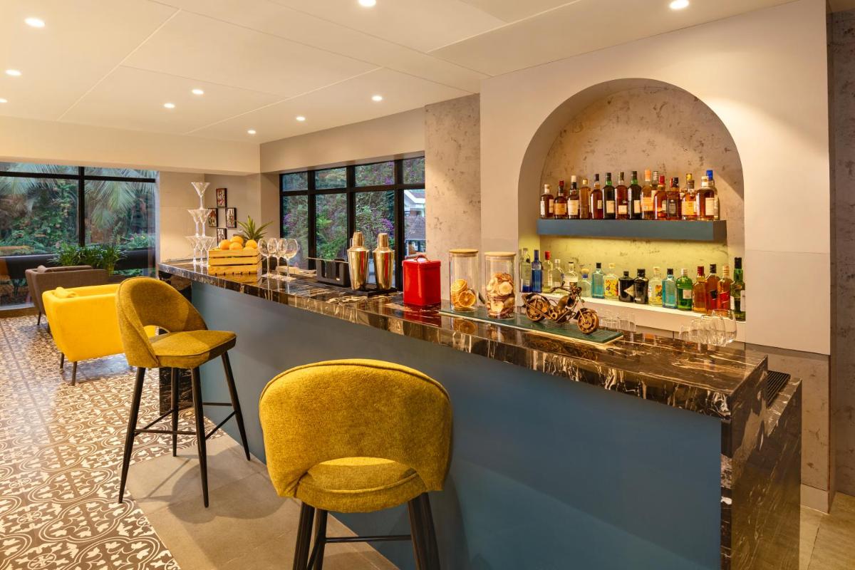 a bar with yellow stools and a counter with drinks at Hyatt Place Goa Candolim in Candolim a bar with yellow stools and a counter with drinks at Hyatt Place Goa Candolim in Candolim