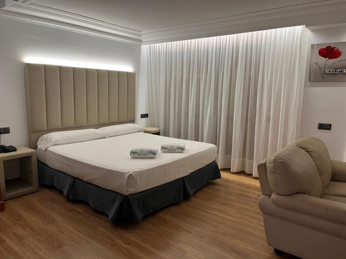 Un dormitorio con una cama, un sofá y una silla. en Gran Hotel Liber & Spa Playa Golf, en Noja