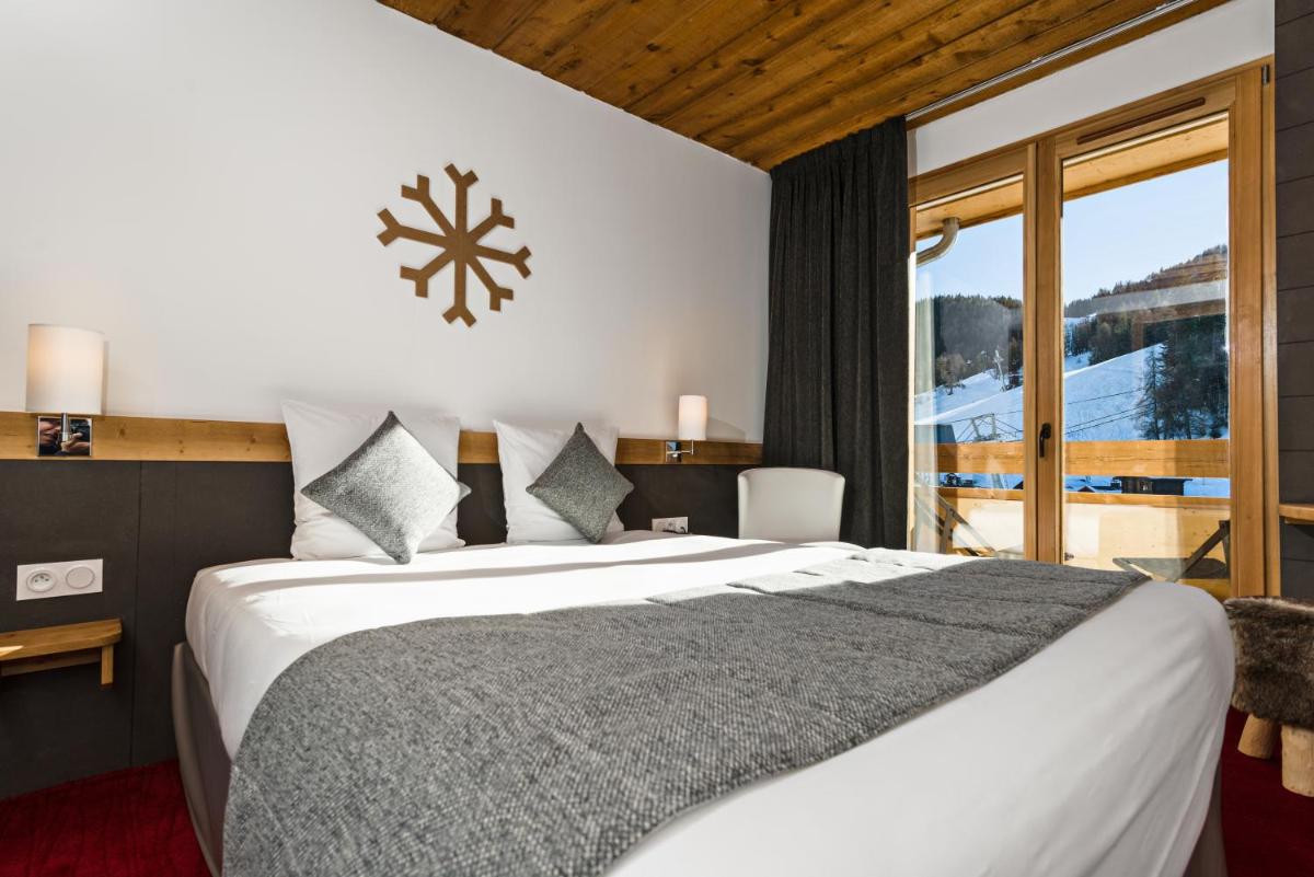 une chambre avec un grand lit et une grande fenêtre dans l'établissement Marmotel & Spa, à Pra-Loup