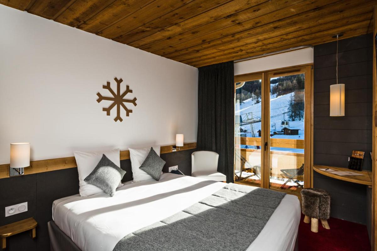 une chambre avec un grand lit blanc et une fenêtre dans l'établissement Marmotel & Spa, à Pra-Loup