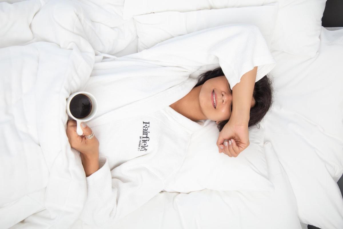 a woman laying in bed with a cup of wine at Fairfield by Marriott Dehradun in Dehradun