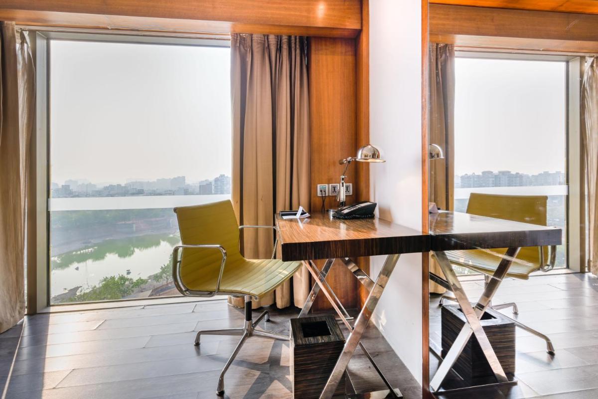 a desk and chairs in a room with a large window at Hyatt Ahmedabad in Ahmedabad