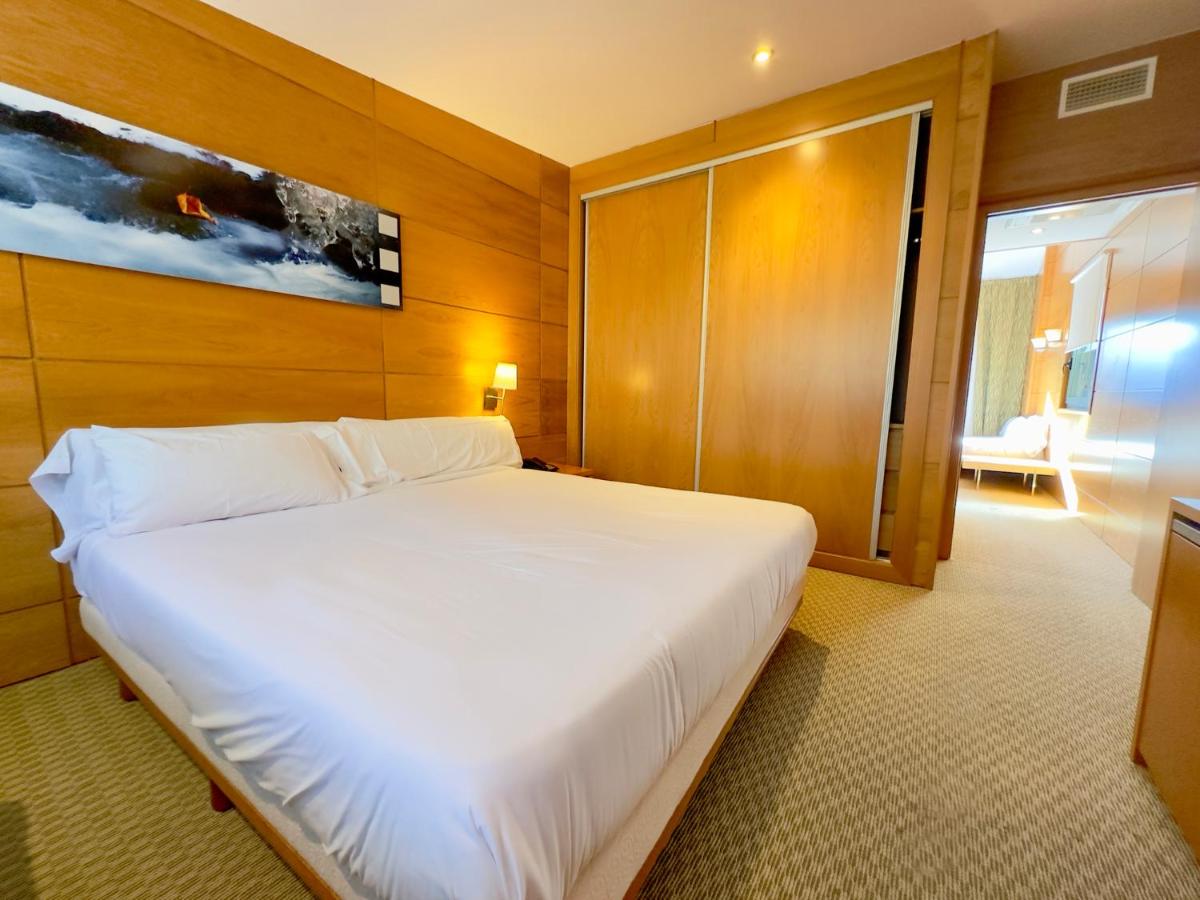 Un dormitorio con una gran cama blanca y una ventana. en Hotel & Spa La Collada, en Toses