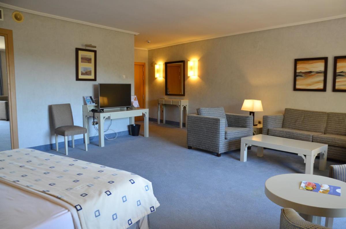 Una habitación de hotel con una cama y una sala de estar. en Beatriz Toledo Auditorium & Spa, en Toledo
