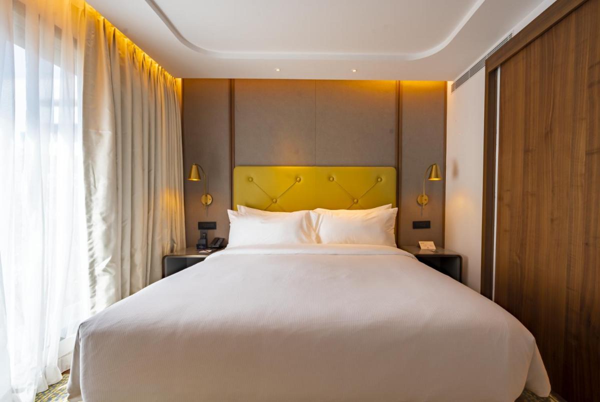 a bedroom with a large white bed with a yellow headboard at Doubletree By Hilton Bengaluru Whitefield in Bengaluru