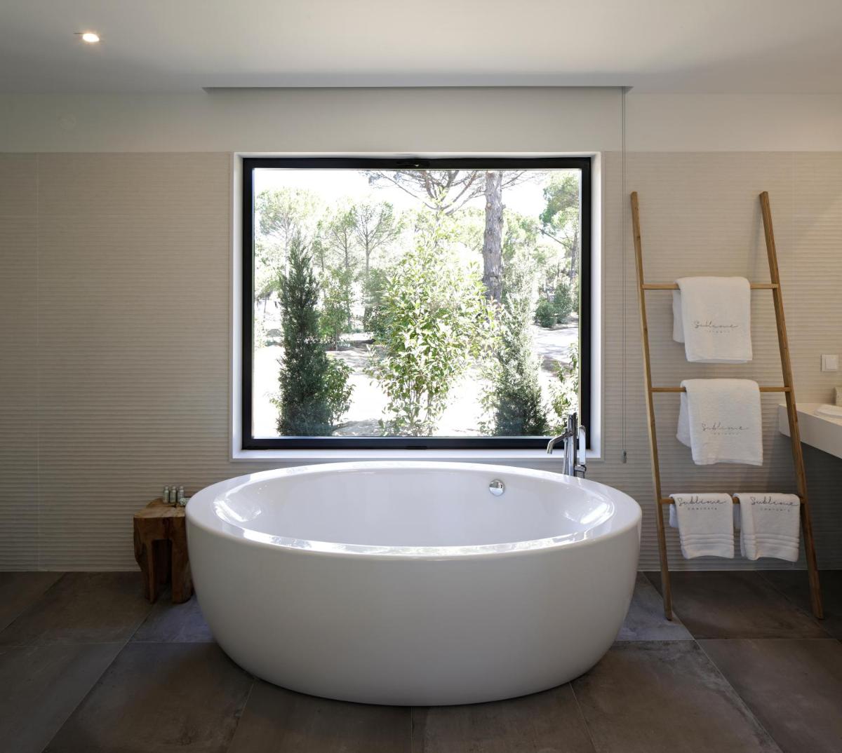 uma grande banheira branca em um banheiro com janela em Sublime Comporta Country Retreat & SPA na Comporta