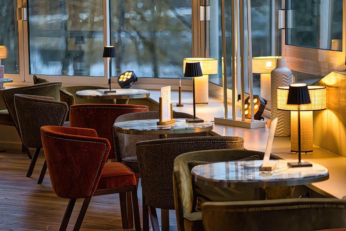 un restaurant avec des tables, des chaises et des lampes dans l'établissement Best Western Plus Le Roi Arthur Hôtel & Spa, à Ploërmel
