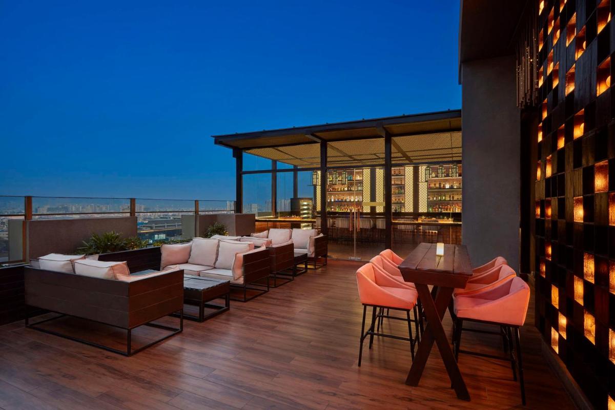 a rooftop patio with couches and tables on a building at DoubleTree by Hilton Gurugram Baani Square in Gurgaon