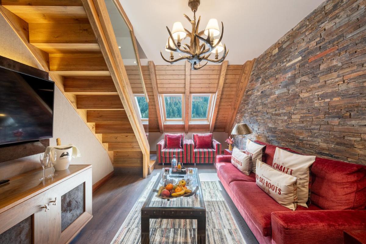 sala de estar con sofá rojo y pared de ladrillo en Hotel Val de Neu G.L., en Baqueira Beret