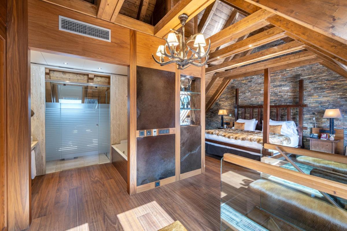 1 dormitorio con techo de madera y pared de ladrillo en Hotel Val de Neu G.L., en Baqueira Beret
